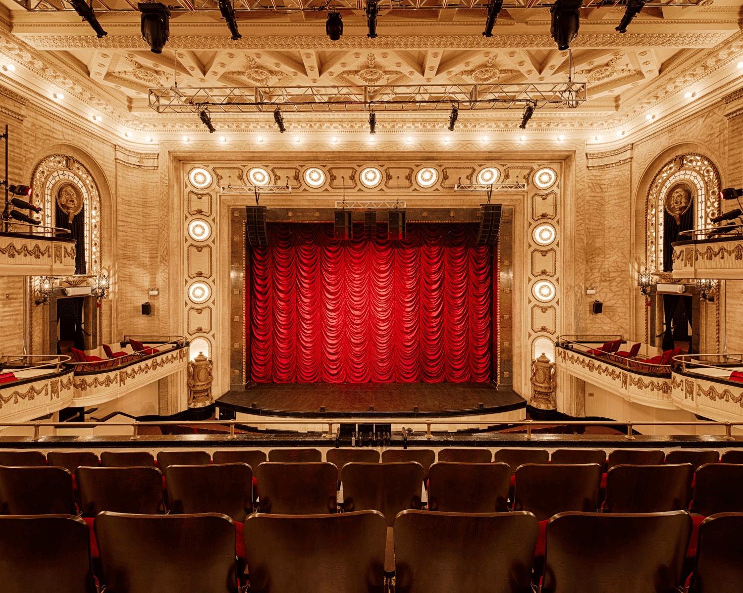 A gilded Broadway proscenium with the red curtain down
